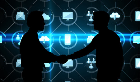 Smiling young businessmen shaking hands in office against apps interface
