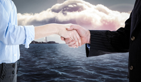 Close up of a business people closing a deal  against calm sea with lighthouseの写真素材