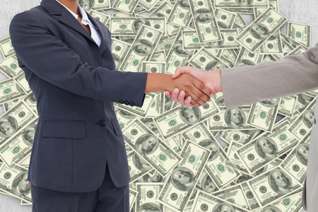 Side view of hands shaking against pile of dollarsの写真素材