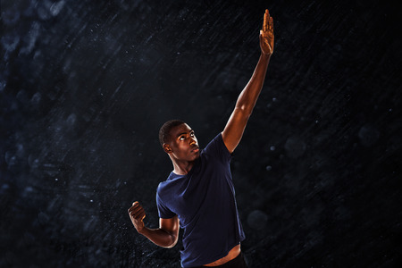Serious young man with hand gestures against black background