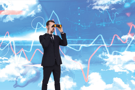 Elegant businessman standing and using binoculars  against blue skyの写真素材
