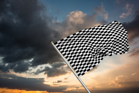 Checkered flag against blue and orange sky with cloudsの写真素材