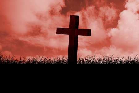 Wooden cross against red sky over grassの写真素材