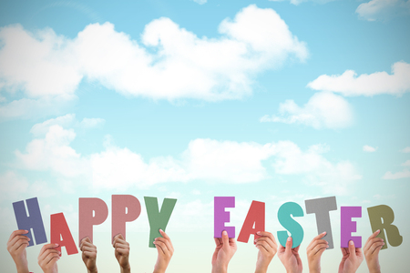 Hands holding up happy easter against blue skyの写真素材