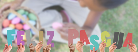 Hands holding up feliz pasqua against little girl sitting on grass counting easter eggsの写真素材