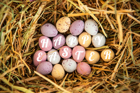 happy easter against little candy easter eggs in straw