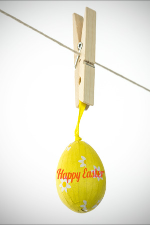 happy easter against yellow easter egg hanging from a lineの写真素材
