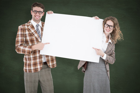 Geeky hipster couple holding poster against green chalkboard
