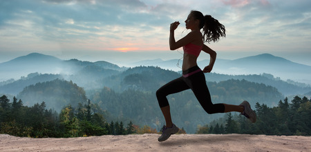 Full length of healthy woman jogging  against misty landscape