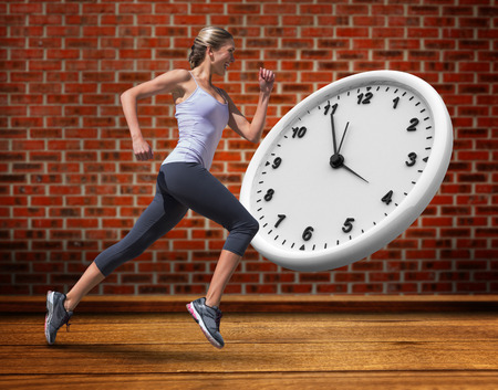 Pretty fit blonde jogging  against room with brick wallの写真素材