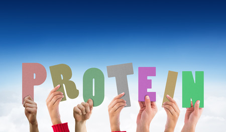 Hands holding up protein against blue sky over cloudsの写真素材