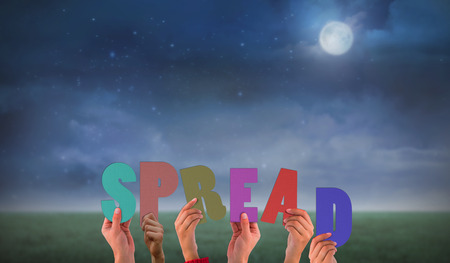 Hands holding up spread against green field at nightの写真素材