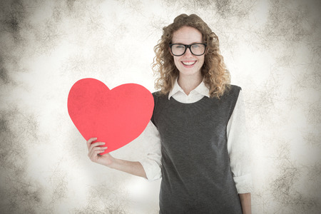 Geeky hipster holding heart card against grey backgroundの写真素材