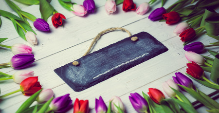 Tulips forming frame around chalkboard on wooden table