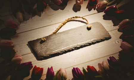 Vintage image of tulips forming frame around chalkboard on wooden tableの写真素材