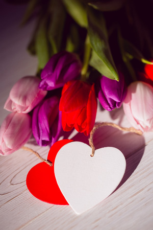 Bunch of tulips and heart card on wooden tableの写真素材