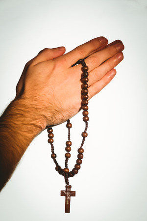 Hand holding wooden rosary beads on white background