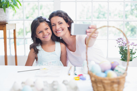Happy mother and daughter taking selfie in the living roomの写真素材