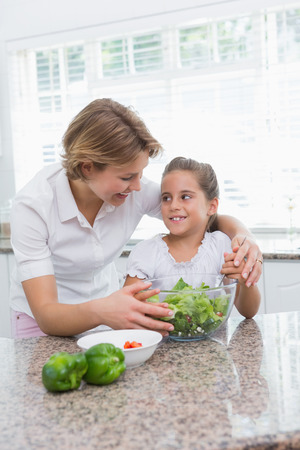 Mother and daughter preparing salad at home in kitchenの写真素材