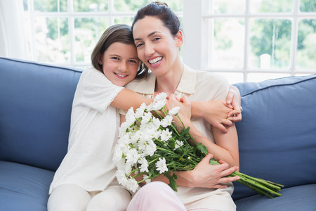 Mother and daughter smiling at camera at home in the living roomの写真素材