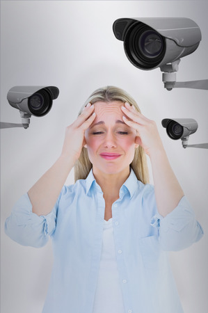 Portrait of a blonde getting a headache against cctv camera