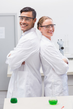 Smiling scientists standing back to back in laboratoryの写真素材