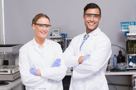 Smiling scientists looking at camera arms crossed in laboratoryの写真素材