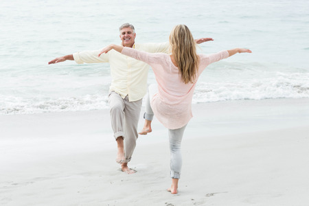 Happy couple doing yoga pose at the beachの写真素材