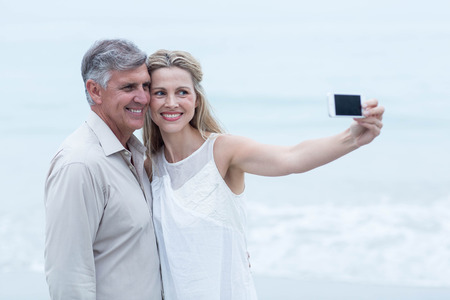 Happy couple taking a selfie at the beachの写真素材