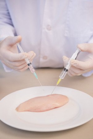 Scientist injecting piece of meat in the laboratoryの写真素材