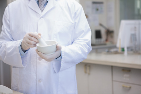 Scientist grinding powder with mortar in the laboratoryの写真素材