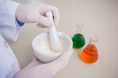 Scientist grinding powder with mortar in the laboratoryの写真素材