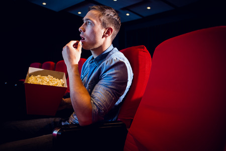 Young man watching a film at the cinemaの写真素材