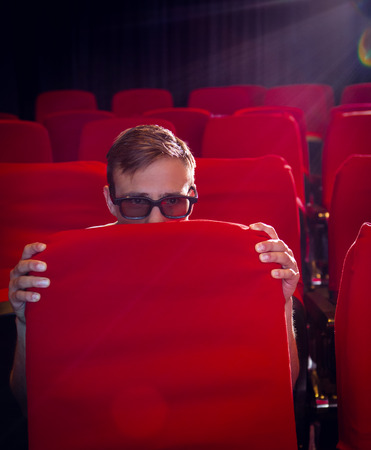 Young man watching a scary 3d film at the cinemaの写真素材
