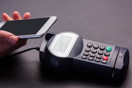 Man using smartphone to express pay against grey background