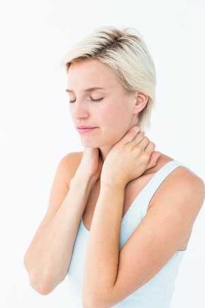 Wincing woman suffering from neck ache on white backgroundの写真素材