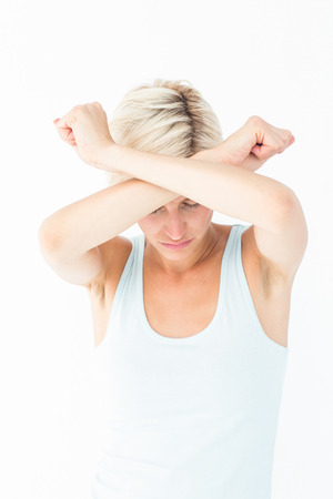 Upset woman holding her arms in front of her headon white backgroundの写真素材