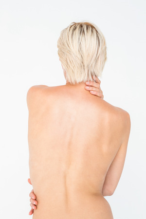 Beautiful topless woman touching her back on white backgroundの写真素材