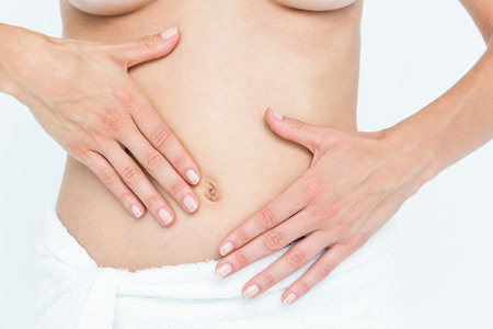 Beautiful woman touching her belly on white background