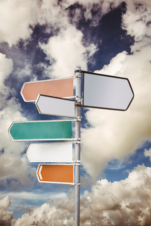 Signpost arrows with copy space against cloudy blue sky