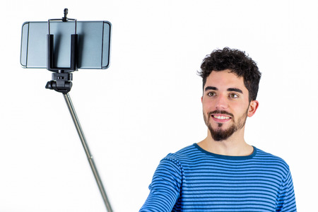 Casual man using a selfie stick shot in studio