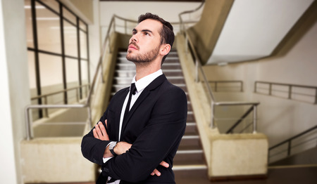 Thinking businessman with his arms crossed against empty stair wayの写真素材
