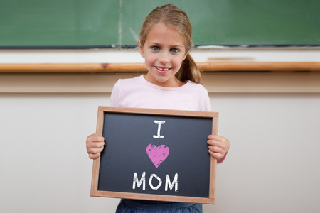 Mothers day greeting against cute pupil showing chalkboardの写真素材