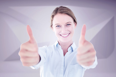 Smiling businesswoman looking at camera against abstract grey roomの写真素材