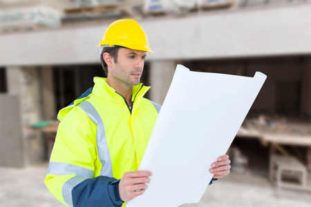 Architect analyzing blueprint over white background against workshop