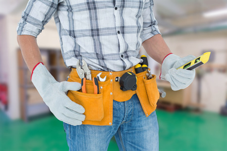 Technician holding spirit level over white background against workshopの写真素材