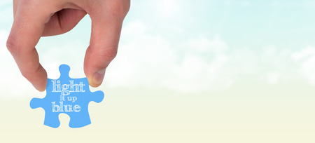 Hand holding jigsaw piece against blue sky