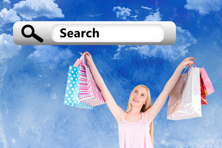 Pretty young blonde holding shopping bags against painted skyの写真素材