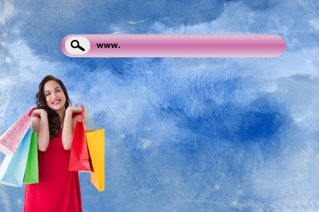 Elegant brunette in red dress holding shopping bags against painted skyの写真素材