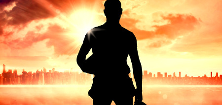 Handyman against sun shining over cityの写真素材